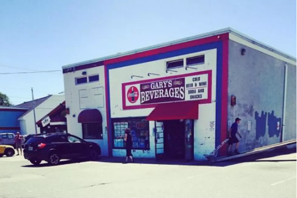 Building with a sign that reads "Gary's Beverages" on the side of it, surrounded by cars on the road, people