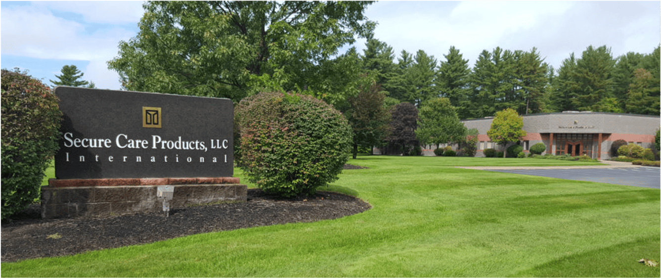 Secure care products, llc international sign in front of a building surrounded by lush green grass, plants, and trees