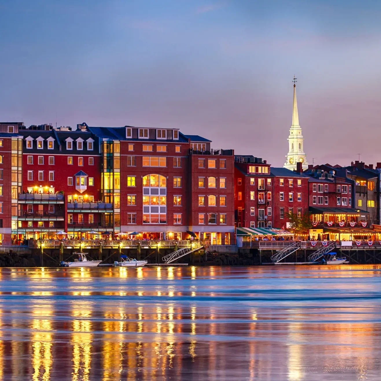 City at dusk from the water, with boats on the surface of the water